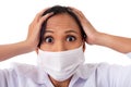 Woman doctor wearing coronavirus surgical face mask in panic scared doing a stressed out facial expression holding head