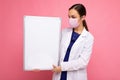 Woman doctor wearing a white medical coat and a mask holding blank board with copy space for text isolated on background Royalty Free Stock Photo