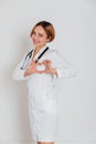 woman doctor in white coat with phonendoscope shows heart with hands Royalty Free Stock Photo