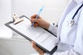 Woman doctor at work at hospital. Young female physician write prescription or filling up medical form while sitting in Royalty Free Stock Photo