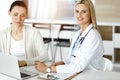 Woman-doctor at work in sunny hospital is happy to consult female patient. Blonde physician checks medical history