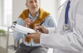 Woman doctor writing on clipboard while talking to senior patient during medical interview Royalty Free Stock Photo