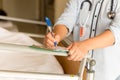 Woman doctor writing medical details of patient