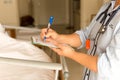 Woman doctor writing medical details of patient