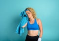 Woman does gym at home. tired expression. cyan background