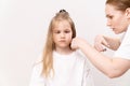 A woman does haircut a funny girl's on a white background.