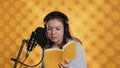 Woman doing voiceover reading of book to produce audiobook, studio background