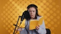 Woman doing voiceover reading of book to produce audiobook, studio background