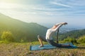 Woman does yoga asana Anjaneyasana in mountains