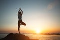 A woman does yoga and meditation on the sea beach during a beautiful sunset. Royalty Free Stock Photo