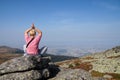 A woman does yoga on the top of a mountain, at the foot of which there is a large metropolis