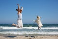 Woman and dog breed Labrador jumping on the beach