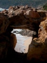 Woman and dog friendship on a beach from far away. Scene framed in a rock window Royalty Free Stock Photo