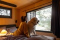 Woman with a dog lying on bed at wooden cabin on nature