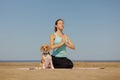 woman and dog meditate on yoga mat on ocean in morning. sports outdoor for mental health Royalty Free Stock Photo