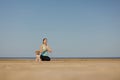 woman and dog meditate on yoga mat on ocean in morning. sports outdoor for mental health Royalty Free Stock Photo