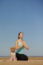 woman and dog meditate on yoga mat on ocean in morning. sports outdoor for mental health Royalty Free Stock Photo