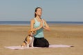 woman and dog meditate on yoga mat on ocean in morning. sports outdoor for mental health Royalty Free Stock Photo