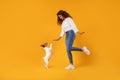 Woman and dog playing against yellow backdrop