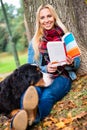 Woman with dog reading book in autumn park Royalty Free Stock Photo