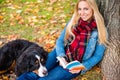 Woman with dog reading book in autumn park Royalty Free Stock Photo