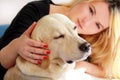Woman with dog is resting in bed at home, relaxing in bedroom. Girl is petting with her dog. Portrait of cute yellow labrador. Royalty Free Stock Photo