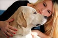 Woman with dog is resting in bed at home, relaxing in bedroom. Girl is petting with her dog. Portrait of cute yellow labrador. Royalty Free Stock Photo