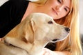 Woman with dog is resting in bed at home, relaxing in bedroom. Girl is petting with her dog. Portrait of cute yellow labrador. Royalty Free Stock Photo