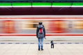 Woman with dog at subway station with blurry moving train