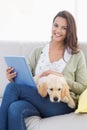 Woman with dog using tablet computer on sofa Royalty Free Stock Photo