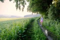 Woman with a dog walking down a gravel path in a country field Royalty Free Stock Photo