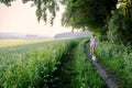 Woman with a dog walking down a gravel path in a country field Royalty Free Stock Photo