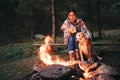 Woman and dog warm near campfire on autumn forest glade