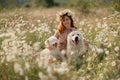 Woman dogs meadow chamomile. Woman embraces her furry friends in a serene chamomile field, surrounded by lush greenery