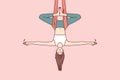 Woman doing aerial yoga hangs upside down in hammock and keeps balance with arms at sides