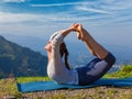 Woman doing Ashtanga Vinyasa Yoga asana Dhanurasana - bow pose