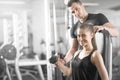 Woman doing bicep curls in gym with her personal trainer Royalty Free Stock Photo