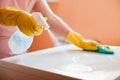 woman doing chores in bathroom at home, cleaning surfaces sink and faucet with spray detergent suds sponge. Royalty Free Stock Photo