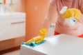 woman doing chores in bathroom at home, cleaning surfaces sink and faucet with spray detergent suds sponge. Royalty Free Stock Photo