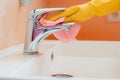 woman doing chores in bathroom at home, cleaning surfaces sink and faucet with spray detergent suds sponge. Royalty Free Stock Photo