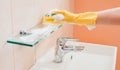 woman doing chores in bathroom at home, cleaning surfaces sink and faucet with spray detergent suds sponge. Royalty Free Stock Photo