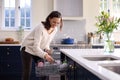 Woman Doing Chores Loading Dishwasher In Kitchen At Home Royalty Free Stock Photo