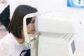 Woman doing eye test with optometrist machine in eye sight clinic.