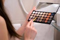 Woman is doing face contouring using coloufrul concealer palette, close-up. Royalty Free Stock Photo