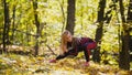 Woman doing fitness exercises outdoor. Female stretching in autumn forest. Slim girl at workout - squats Royalty Free Stock Photo