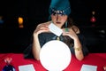 Woman doing fortune telling witchcraft forecasting the future with crystal ball and Tarot card on red table Royalty Free Stock Photo