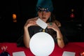 Woman doing fortune telling witchcraft forecasting the future with crystal ball and Tarot card on red table Royalty Free Stock Photo