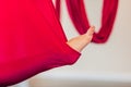 Woman doing full splits in red hammock on aerial yoga class, focus on bare feet.