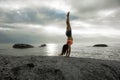 Woman doing a handstand on a rock at sunset on Bakovern Beach, Cape Town.