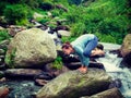 Woman doing Kakasana asana arm balance at waterfall